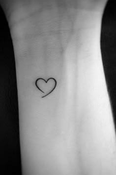 a heart tattoo on the wrist with a small black line in the shape of a heart