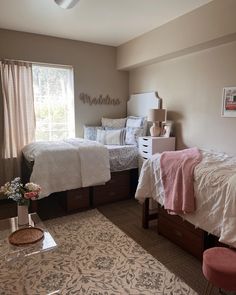 a bedroom with two beds and a rug on the floor next to each other in front of a window