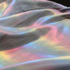 the fabric is shiny and colorful with some light colors on it's surface,