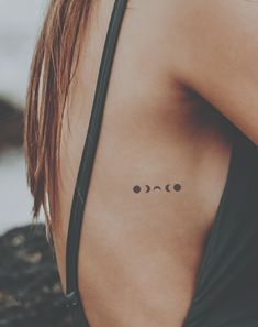 a woman's back with three small circles on her left shoulder and two smaller circles on her right arm