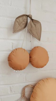 two round pillows hanging on a brick wall next to a wicker basket with an orange pillow