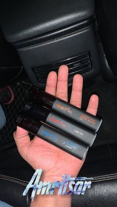 three batteries in the palm of a person's hand on a car seat cushion