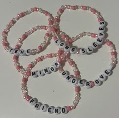 four pink and white beads with words on them