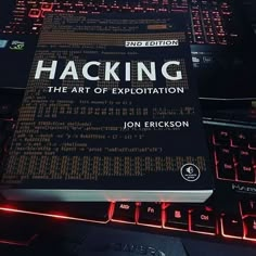 a book sitting on top of a computer keyboard next to a red glowing key board