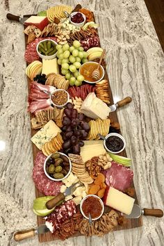 a platter filled with different types of cheeses and crackers on top of a marble counter