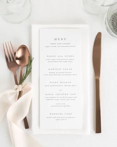 a table setting with utensils, silverware and menu cards on it's side