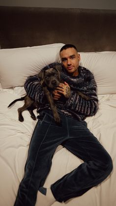 a man laying on top of a bed holding a dog