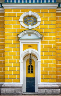 a yellow brick building with a clock on it's face and arched window above the door