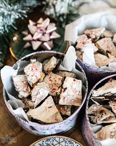 three tins filled with christmas treats sitting on top of a table next to a plate