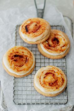 four cinnamon rolls sitting on top of a cooling rack