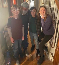 three girls and one boy are standing in front of the door with their helmets on