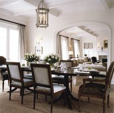 a formal dining room with white walls and beige carpeted flooring is seen in this image