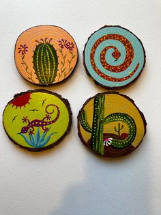 four painted wooden slices with cactus and lizard designs on them, hanging from the wall