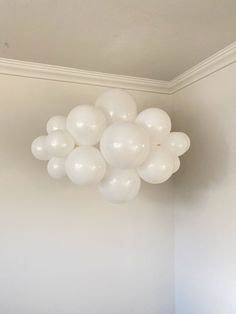 a bunch of white balloons hanging from the ceiling in a room with no one around