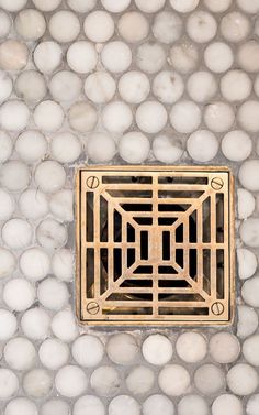 a drain in the middle of a wall with white balls on it's sides