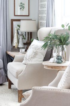 a living room filled with white furniture and lots of greenery on top of it