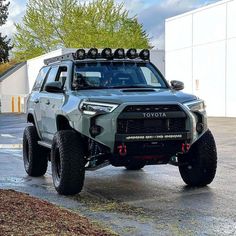 a gray toyota truck parked on top of a parking lot next to a white building