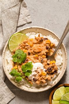 two bowls filled with rice, chicken and cilantro garnished with limes