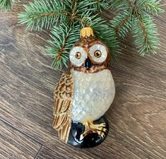 an owl ornament hanging from a pine tree