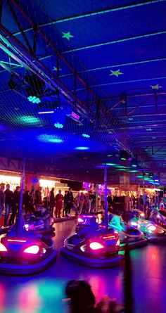 people are riding bumper cars in an indoor area with blue lights and stars on the ceiling