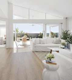 a living room filled with white furniture and windows