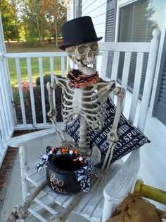 a skeleton sitting on a porch with a top hat