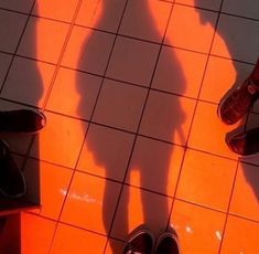 two people standing in front of a tiled floor with their shadows on the ground and one person's shadow