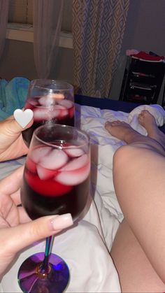 two people toasting with drinks on a bed