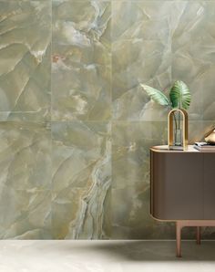 a modern bathroom with green marble tiles on the wall and a plant in the corner