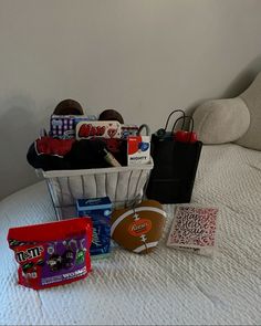 a white bed topped with lots of items next to a bag on top of it