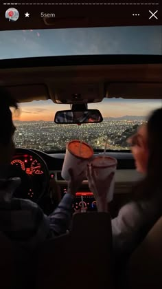 two people sitting in the back seat of a car, one is holding a drink