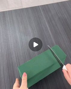 someone cutting paper with a pair of scissors on top of the floor next to a green box