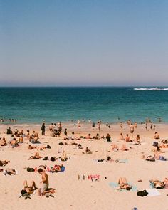 many people are on the beach and one is flying a kite in the sky above them