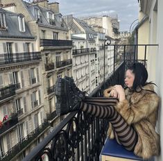 a woman sitting on top of a balcony next to tall buildings