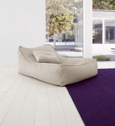 a bean bag chair sitting on top of a purple rug in front of a window