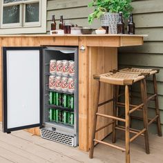 an outdoor bar with a cooler and two stools next to it on a deck