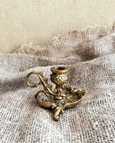 a golden candle holder sitting on top of a white cloth