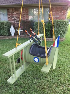 a green swing with fishing rods attached to it in front of a brick house on the lawn