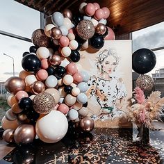 a table topped with lots of balloons next to a painting and vase filled with flowers