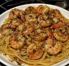 pasta with shrimp and parmesan cheese in a white bowl on top of a stove