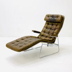 a brown leather reclining chair and footstool on a white floor with a white wall in the background