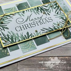 a merry christmas card with pine branches and gold trimmings on the edge, in front of a wooden background