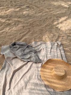 a hat and shirt laying on a blanket at the beach