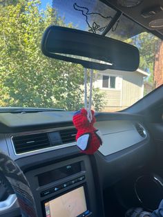 a red teddy bear hanging from the dashboard of a car