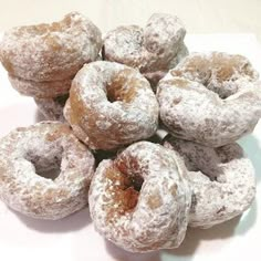 a pile of powdered donuts sitting on top of a white plate