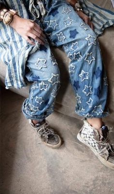 a person sitting on top of a couch wearing blue jeans and white converse shoes with stars all over them