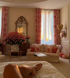 a woman laying on top of a bed in a room with red and white curtains