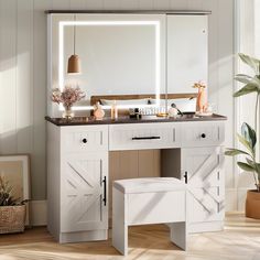 a white vanity with mirror, stool and lights on it in front of a potted plant