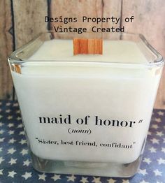 a candle that is sitting on top of a blue and white table cloth with the words maid of honor written across it