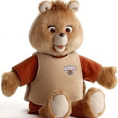 a brown teddy bear sitting on top of a white floor